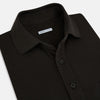 View 2 of product A brown short-sleeve polo shirt by Turnbull & Asser, crafted from pure cotton jersey with a collar, three buttons, and a buttoned chest pocket, laid flat on a white background.