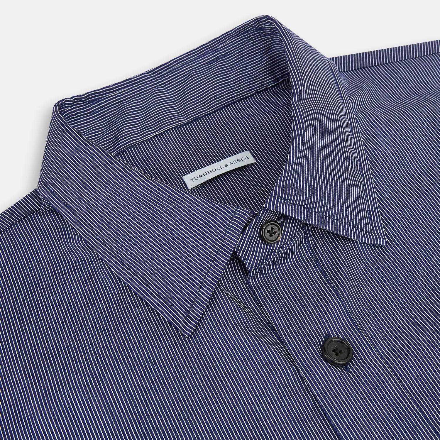 View 2 of product The Navy Stripe Highbury Overshirt by Turnbull & Asser features thin vertical stripes, black buttons, a collar, and a chest pocket. Displayed on a plain white background, it’s inspired by classic Turnbull & Asser style.