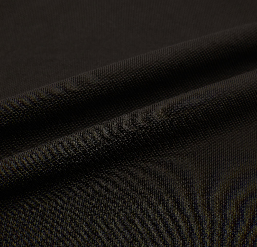 A brown short-sleeve polo shirt by Turnbull & Asser, crafted from pure cotton jersey with a collar, three buttons, and a buttoned chest pocket, laid flat on a white background.